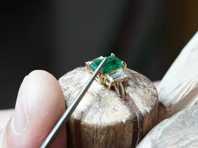An emerald ring being set at a jeweller's bench, and three VanHess diamond rings