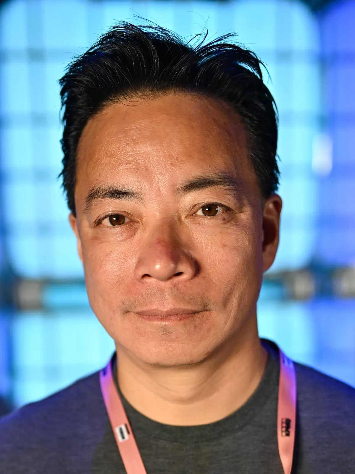 Portrait of Ken Sim at Collision 2024, with a blue background.
