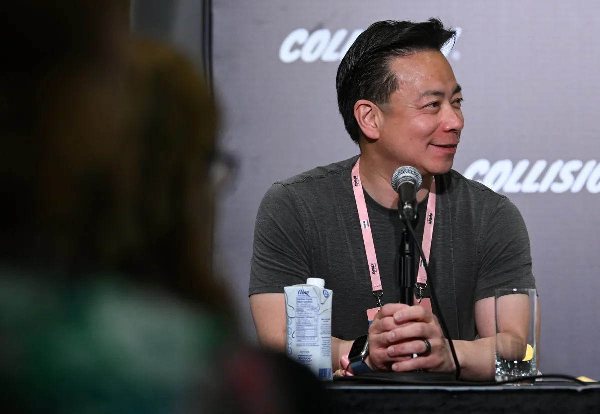 Ken Sim seated at a microphone during a Collision 2024 press conference.