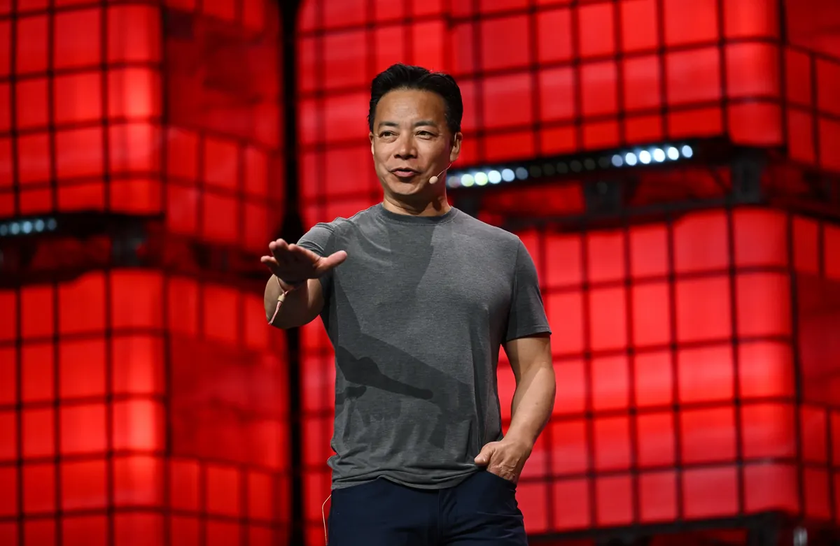 Ken Sim speaking with a headset microphone on the red Collision 2024 stage.
